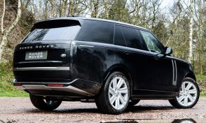 Schwarzer SUV auf schlammigem Waldweg mit Pfützen – SUV-Aufnahme im Gelände bei bewölktem Wetter