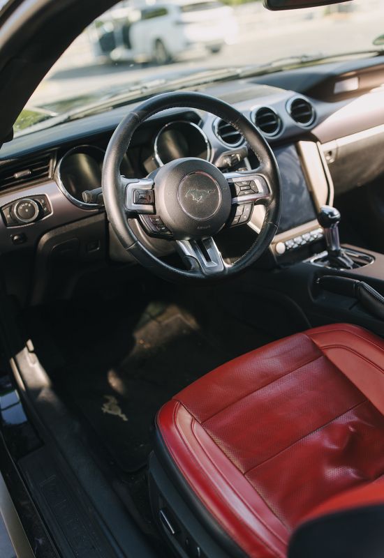 Innenraum eines Ford Mustang mit rotem Ledersitz und gepflegtem Cockpit – Fokus auf Fahrzeugaufbereitung