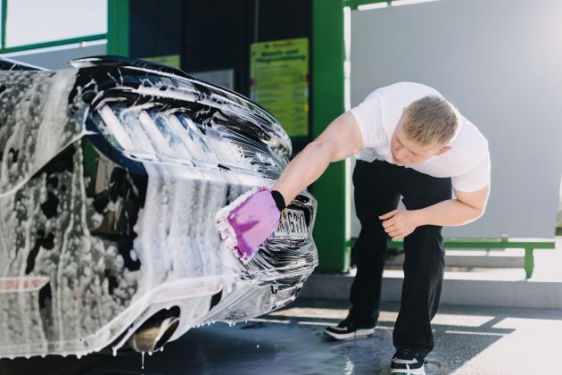 Autopfleger reinigt Fahrzeug-Heck mit Waschhandschuh und Schaum – gründliche Handwäsche bei Max UP Autopflege
